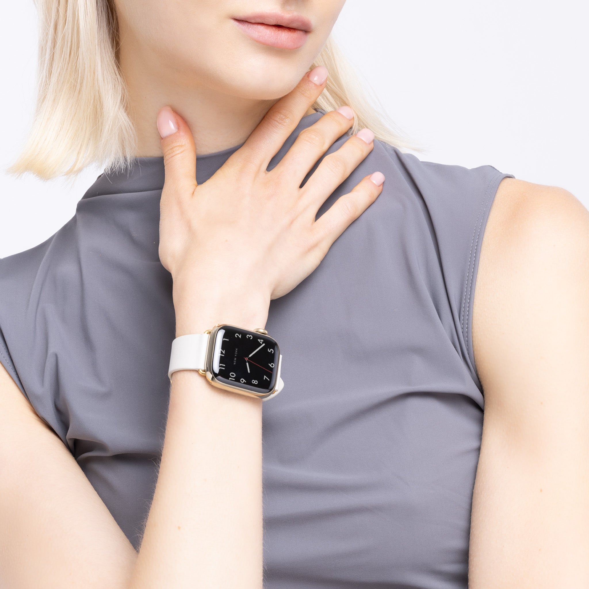 A woman wearing an Apple Watch with a white leather band.
