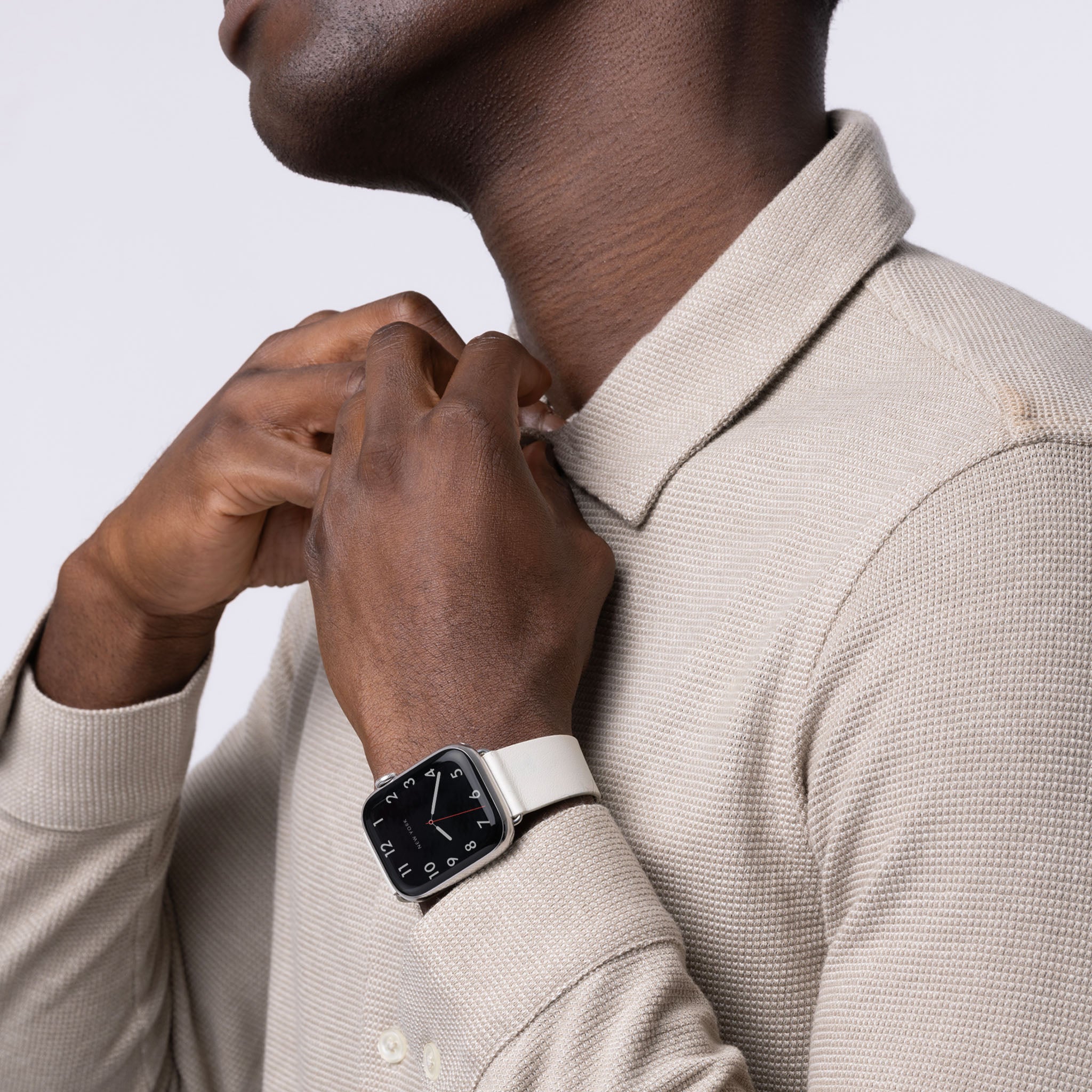 A man wearing an Apple Watch with a white leather band.